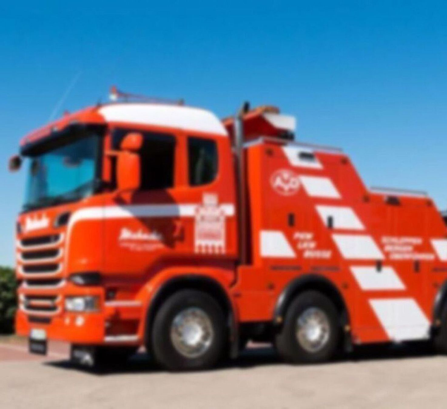 Bild eines roten Abschleppwagens auf einem Parkplatz unter blauem Himmel